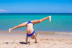 menina adorável fazendo roda na praia de areia branca tropical foto