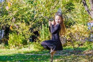 adorável menina fantasiada de bruxa de halloween se divertindo na vassoura foto