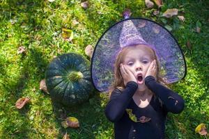 menina bonitinha no halloween que fantasia se diverte ao ar livre foto