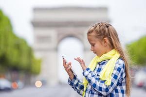 menina adorável da criança com telefone na Champs-Elysees em Paris durante as férias de verão foto