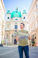 homem turista com um mapa da cidade e mochila na rua da europa. menino caucasiano olhando com mapa da cidade europeia. foto