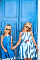 meninas felizes em vestidos na rua da típica aldeia tradicional grega na ilha de mykonos, na grécia foto