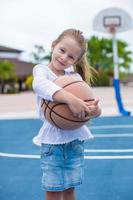 menina com basquete na quadra no resort tropical foto