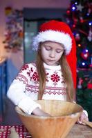 adorável menina fazendo biscoitos de gengibre para o natal foto