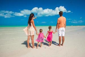 vista traseira família de quatro pessoas em férias na praia do caribe