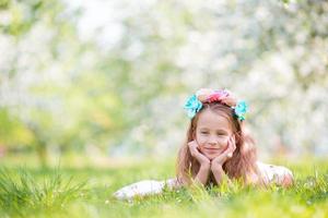 retrato de uma linda garotinha no jardim de macieiras florescendo na primavera foto