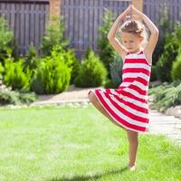 menina adorável em pé em uma pose de ioga em uma perna foto