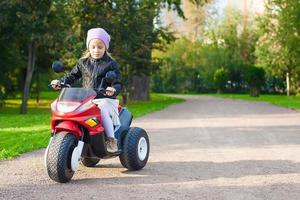 menina adorável se divertindo em sua motocicleta de brinquedo foto