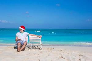 jovem de chapéu de Papai Noel durante as férias na praia foto