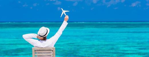 jovem com miniatura de um avião na praia tropical foto