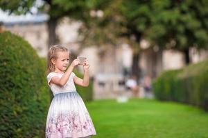 adorável menina com telefone em paris durante as férias de verão foto