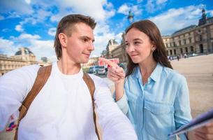 família jovem feliz com mapa da cidade tomando selfie em paris ao ar livre foto