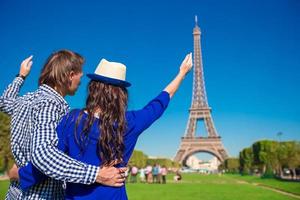 jovem casal feliz no champ de mars em paris ao fundo da torre eiffel foto