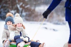 meninas gostam de um passeio de trenó. trenó infantil. as crianças brincam ao ar livre na neve. férias em família na véspera de natal ao ar livre foto