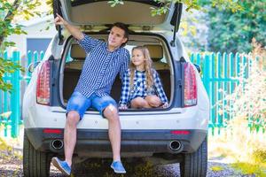 menina com o pai sentado em um carro pouco antes de sair para um carro de férias foto