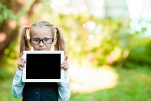 adorável menina segurando o tablet pc ao ar livre em dia ensolarado de outono foto