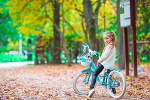 adorável garota andando de bicicleta no lindo dia de outono ao ar livre foto