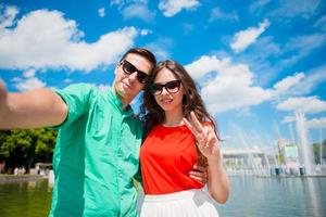 jovens amigos turistas viajando de férias na europa sorrindo felizes. menina caucasiana e homem fazendo fundo selfie da fonte foto