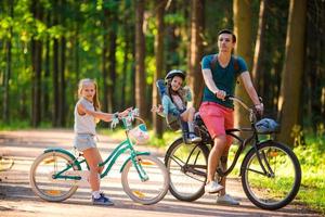 família feliz andando de bicicleta ao ar livre no parque. esporte e crianças ativas e pai gostam de andar de bicicleta ao ar livre foto