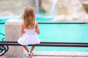 adorável menina olhando para a fonte de trevi em roma. foto