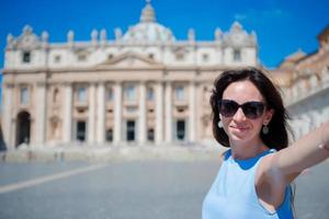 mulher jovem feliz tomando selfie em st. igreja basílica de pedro na cidade do vaticano, roma. bela turista caucasiana fazendo foto de selfie em férias na europa na itália.