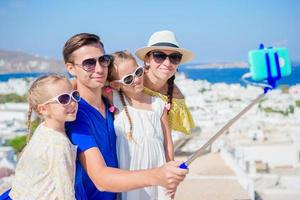 férias em família na europa. pais e filhos tirando selfie foto fundo cidade de mykonos na grécia