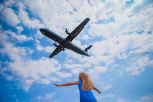 menina bonitinha olhando para o céu e voando de avião diretamente acima dela foto