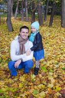 vista traseira do jovem pai e filha andando no parque outono foto