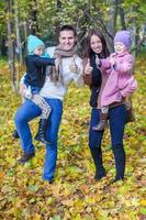 pais jovens com duas filhas pequenas no outono parque amarelo foto