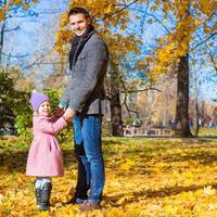 menina adorável com pai feliz no parque no outono foto