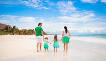 vista traseira da jovem família olhando para o mar na praia do méxico foto