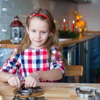 menina adorável fazendo biscoitos de natal em casa foto