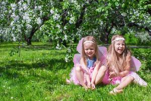 meninas com asas de borboleta no pomar de maçã em flor foto