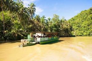 barco de cruzeiro exótico com turistas em um rio de selva loboc, bohol foto