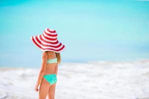 adorável menina com grande chapéu vermelho na praia tropical foto