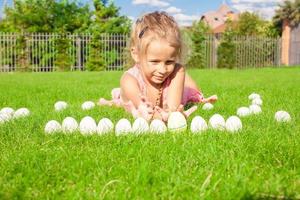 retrato de uma menina adorável brincando com ovos de páscoa brancos no quintal foto