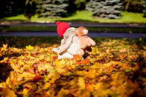 menina adorável com uma mochila-urso caminha na floresta de outono em lindo dia ensolarado foto
