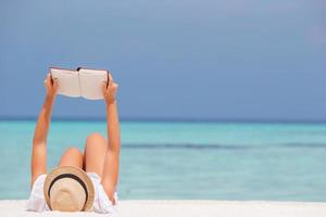 jovem lendo livro durante a praia branca tropical foto