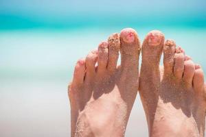 close-up de pés femininos na praia de areia branca foto