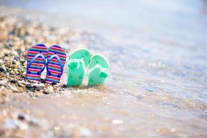 chinelos infantis na praia em frente ao mar foto