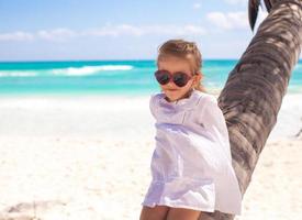 retrato de uma menina adorabe sentada na palmeira na praia caribenha perfeita foto