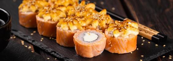 rolo de banner com sushi de peixe com close-up de pauzinhos - conceito de comida asiática foto