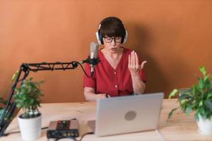 apresentadora de rádio feminina de meia-idade falando no microfone e lendo notícias - conceito on-line de transmissão de rádio foto