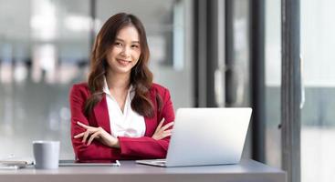 retrato de mulher asiática de negócios linda sorridente em terno rosa trabalhando na mesa de escritório em casa usando o computador. e-commerce de marketing on-line freelancer de funcionários de pessoas de negócios, conceito de trabalho em casa foto