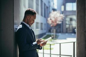 jovem empresário americano africano em traje de negócios formal em pé trabalhando com tablet foto