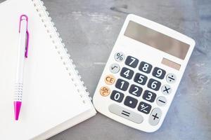 calculadora e bloco de notas em um fundo cinza