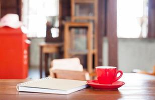 xícara de café vermelha com um notebook em uma mesa de madeira foto