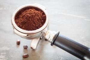 moedor de café com grãos de café em uma mesa foto