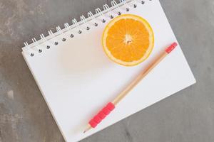 lápis e laranja em um caderno foto