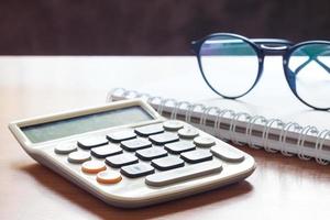 calculadora com óculos em uma mesa de madeira foto